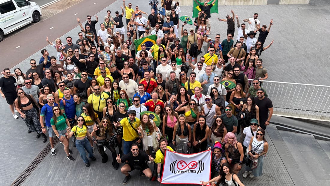 Grupo grande da Never Ends visto do alto com a bandeira da agência, na Tomorrowland Bélgica 2026