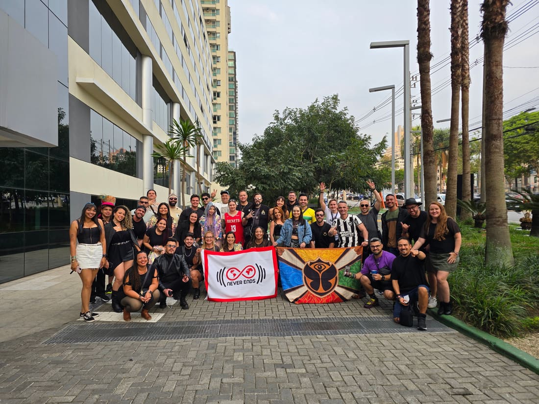 Grupo da Never Ends reunido na saída do hotel em 2024, com as bandeiras da agência e da Tomorrowland Brasil