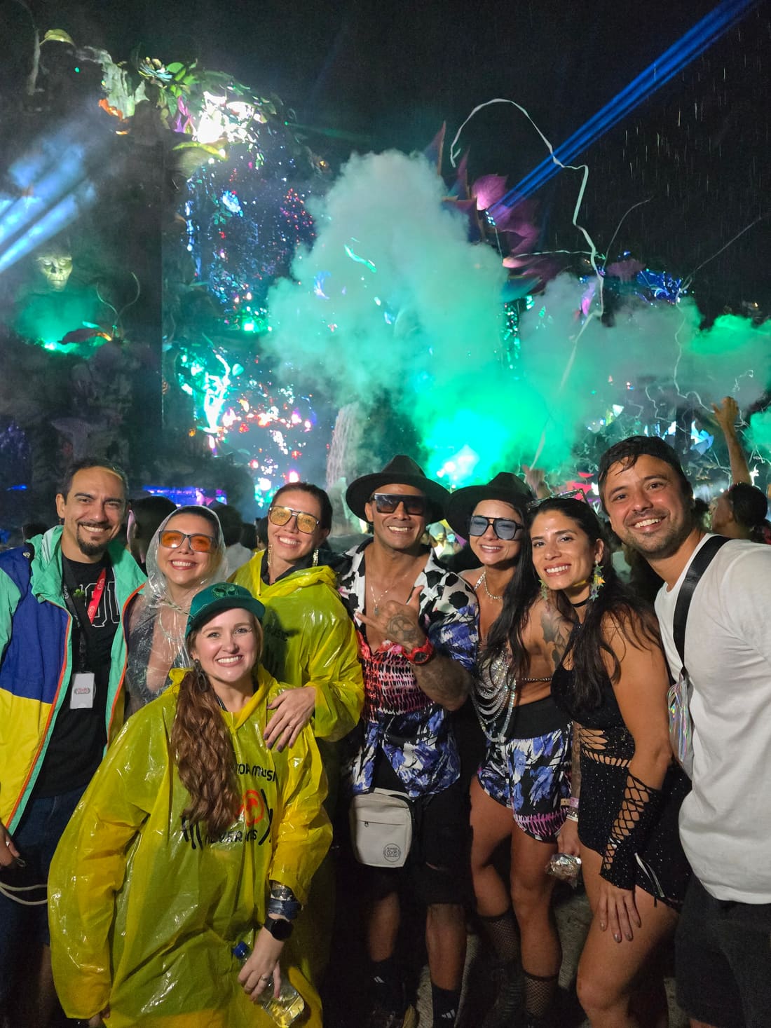 Turma da Never Ends de capa de chuva em meio à fumaça verde de um palco da Tomorrowland Brasil, à noite