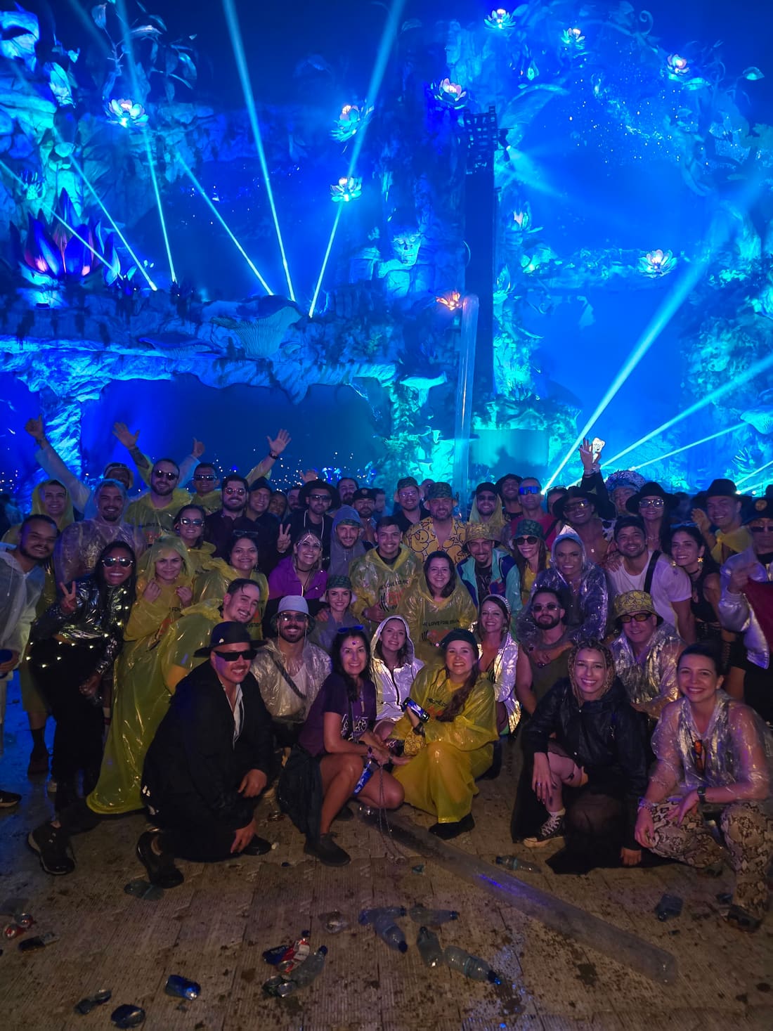 Grupo grande da Never Ends de capa de chuva diante do palco azul da Tomorrowland Brasil, curtindo mesmo debaixo de chuva